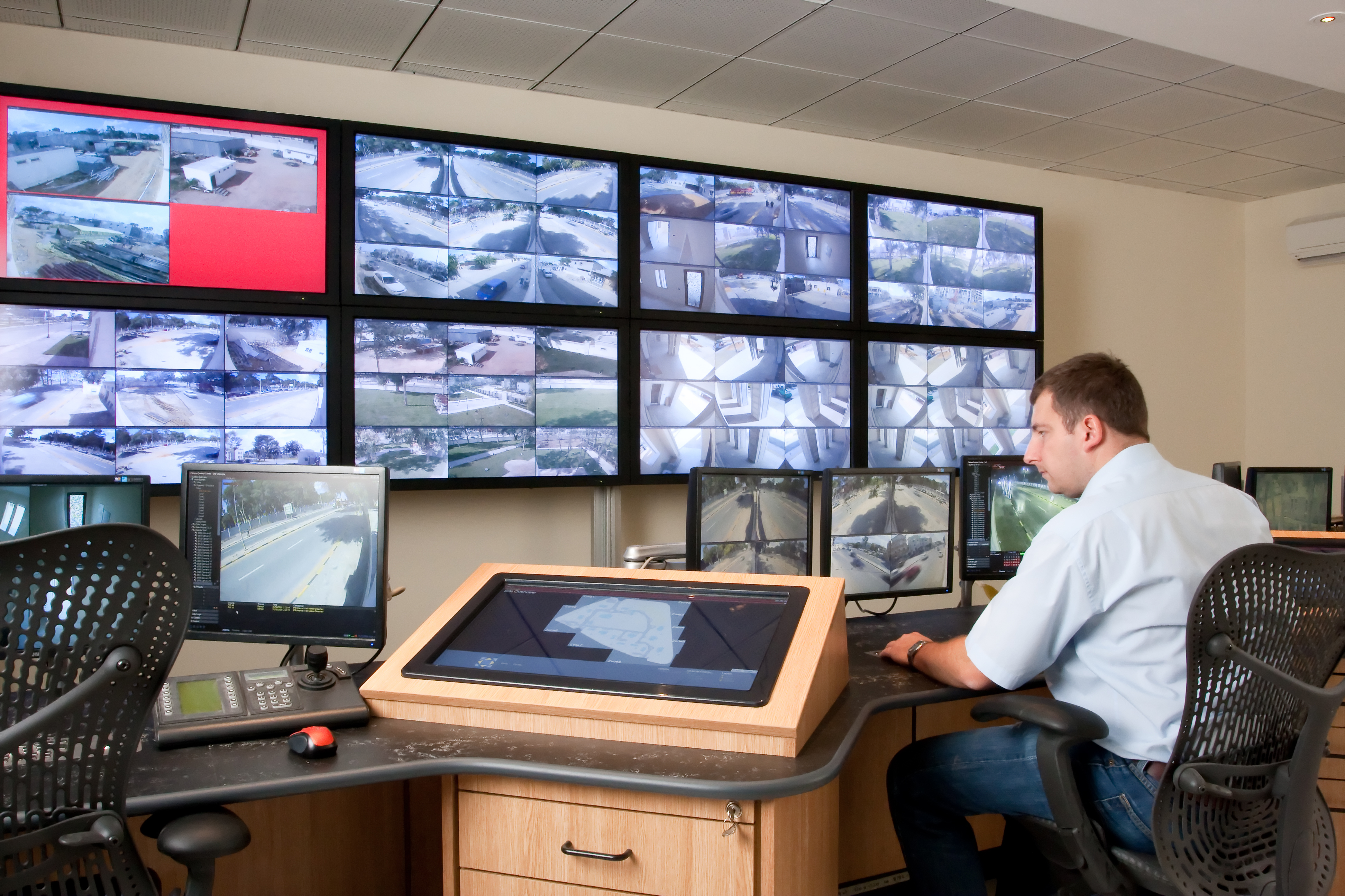 Man monitoring cctv cameras in modern control room